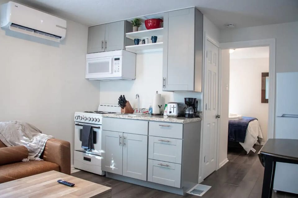 Efficient kitchenette with white cabinetry, electric range, and coffee maker.