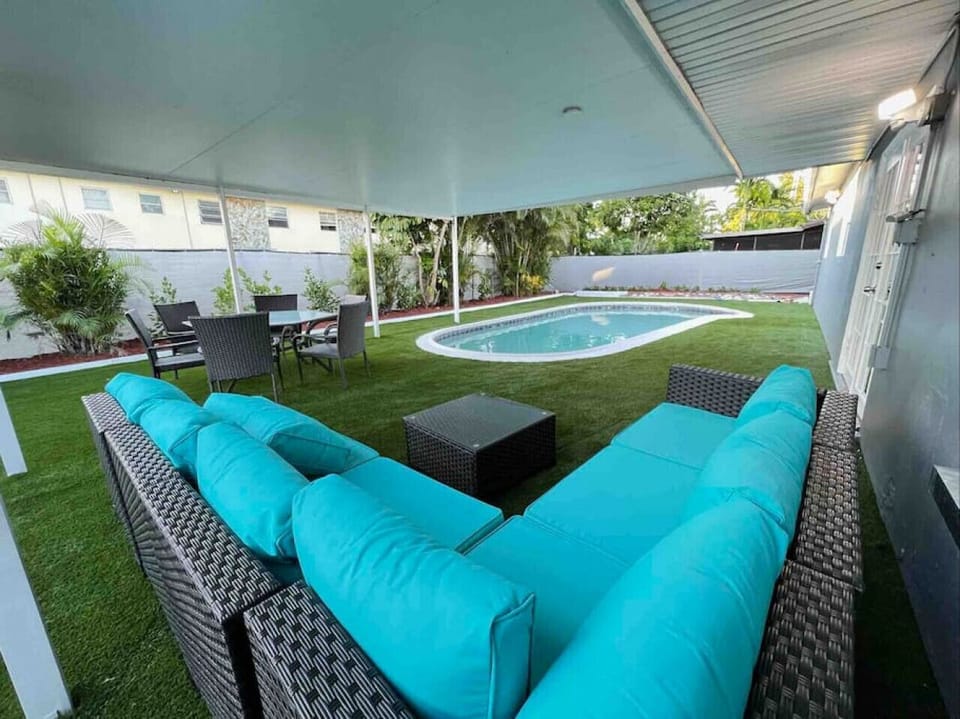 Partially covered backyard with comfortable patio furniture and a pool for those sunny South Florida days