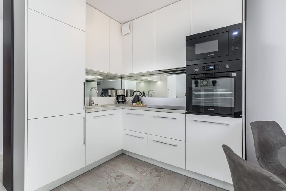 Stylish kitchenette with white furniture and quality appliances. 