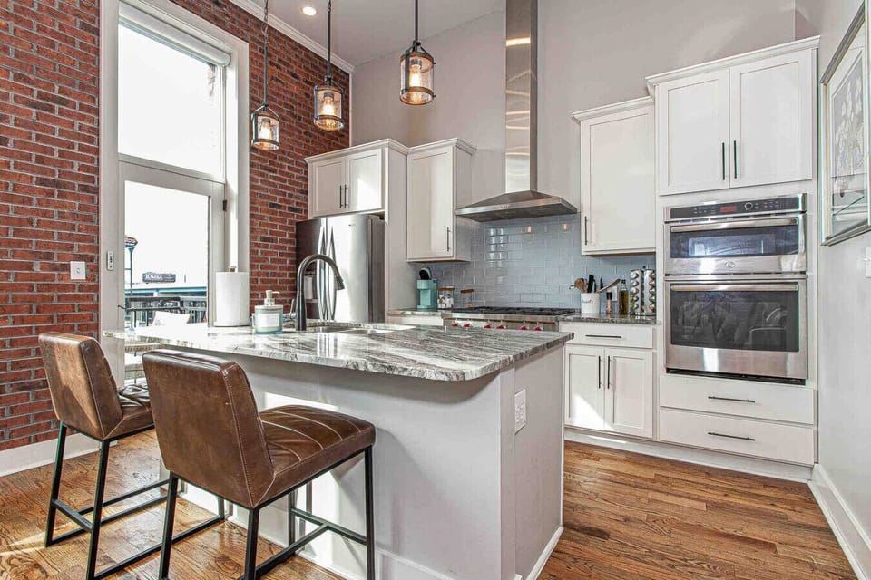 Kitchen: Chic open kitchen with sleek stainless steel appliances and stunning brick accents!