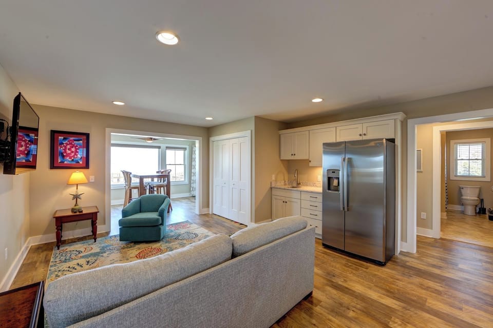 Your open-concept living space flows beautifully from cozy seating to a fully-equipped kitchen with stainless steel appliances and warm hardwood floors throughout.