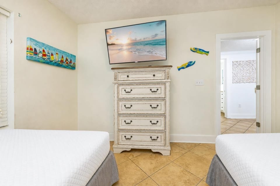 Queen beds in the guest suite frame your view of the dresser and TV for a restful night indoors