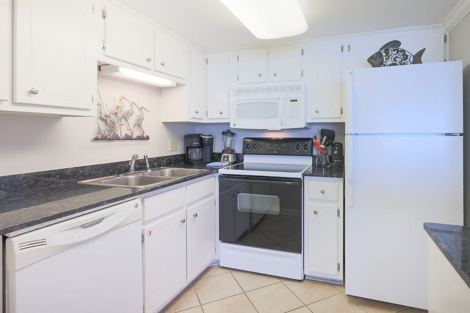 This kitchen features white cabinetry, sleek countertops, and essential appliances for a delightful cooking experience