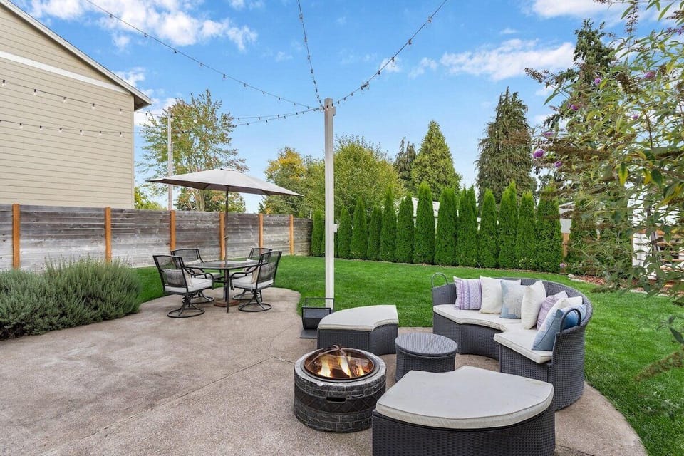 Fenced backyard with outdoor dining table and a sitting area with fire-pit.