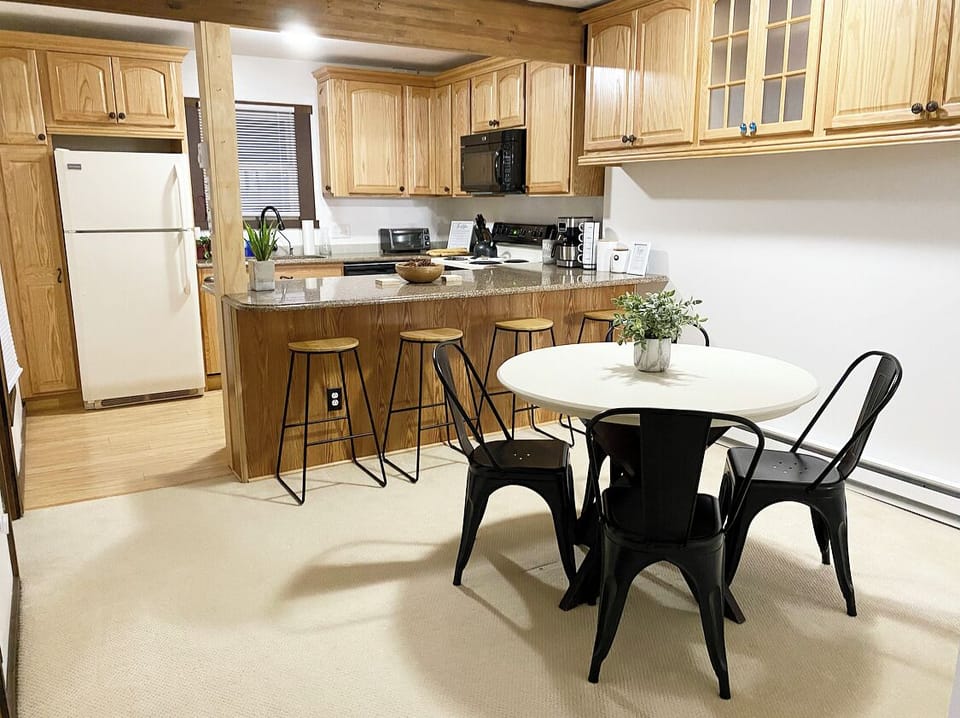 An open kitchen w/ a bar and stools with plenty of counter space. 