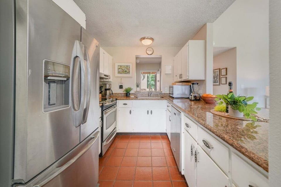 Kitchens brighten with white cabinets and steel, terracotta tiles grounding the design.
