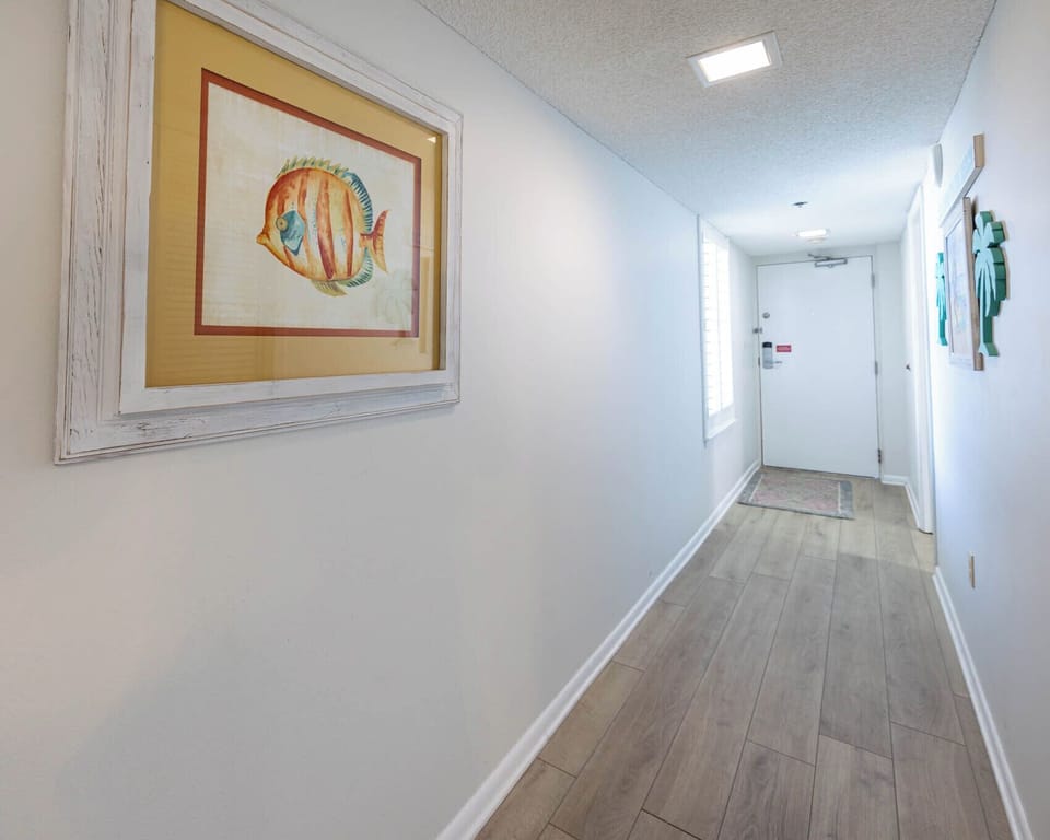Step into a welcoming hallway adorned with coastal art, leading you to your vacation retreat