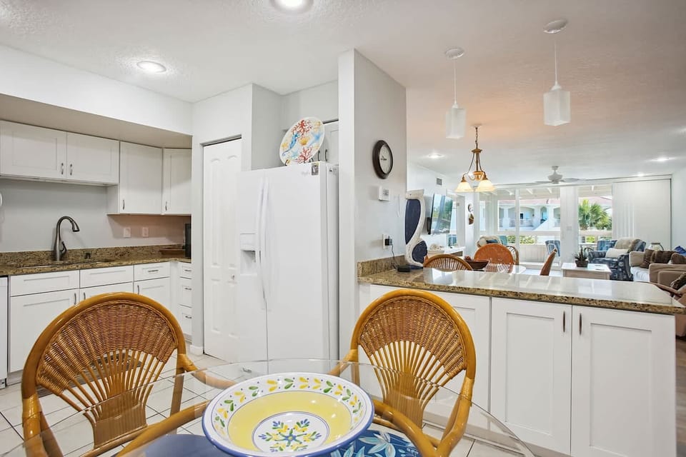 - Enjoy meals or drinks at the kitchen bar with vibrant blue cushioned stools
- White cabinetry and granite counters provide a clean and modern atmosphere
- Great open design connects kitchen seamlessly to the living space