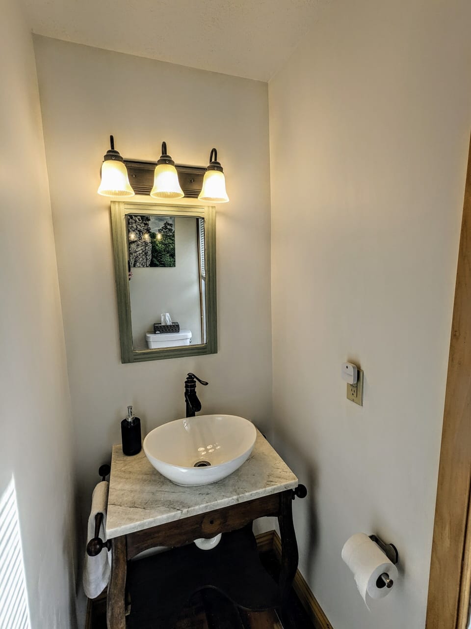 Upstairs half bath features antique washstand base and modern vessel sink.