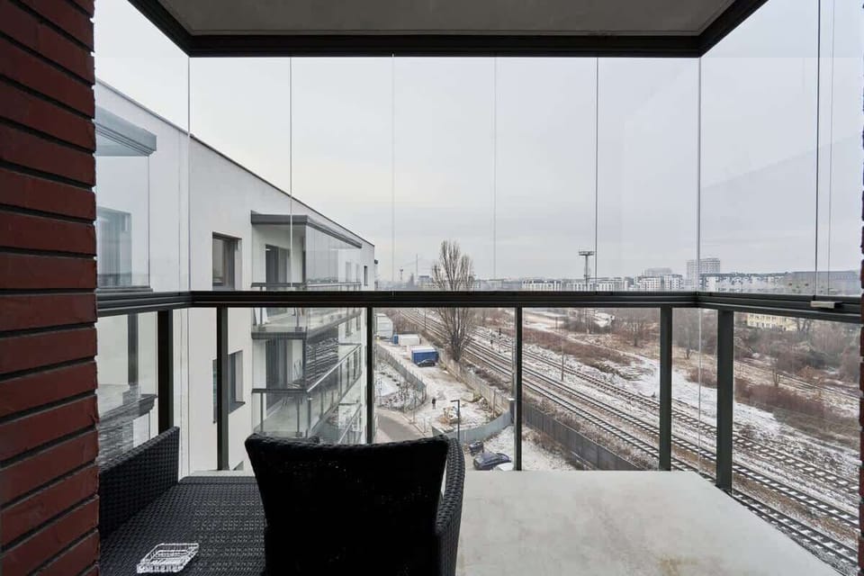 A private balcony space with outdoor seating and a view of the surrounding modern architecture.