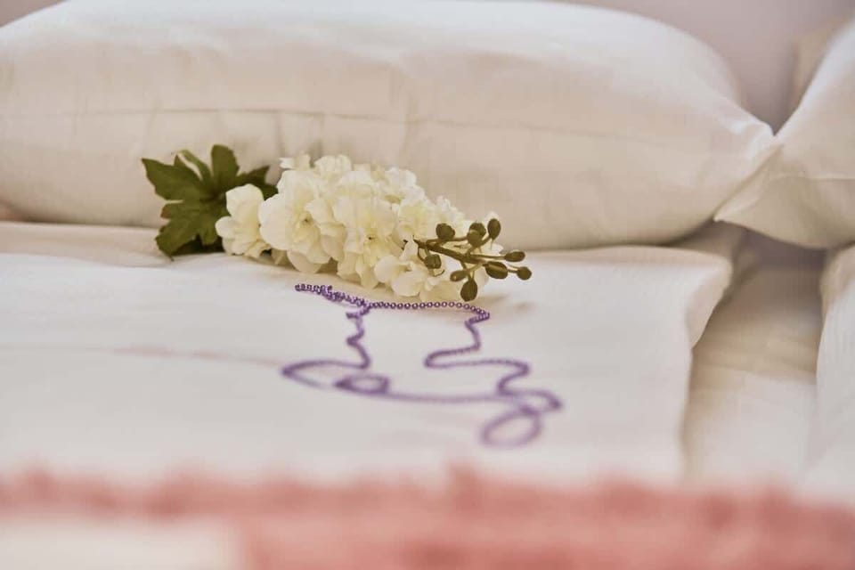 A close-up shot of the bed with white linens and fresh flowers, adding a touch of luxury.