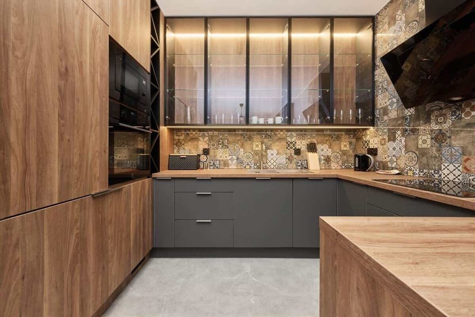 A modern kitchen with wood and black cabinetry, colorful patterned tiles as a backsplash, and high-end appliances.