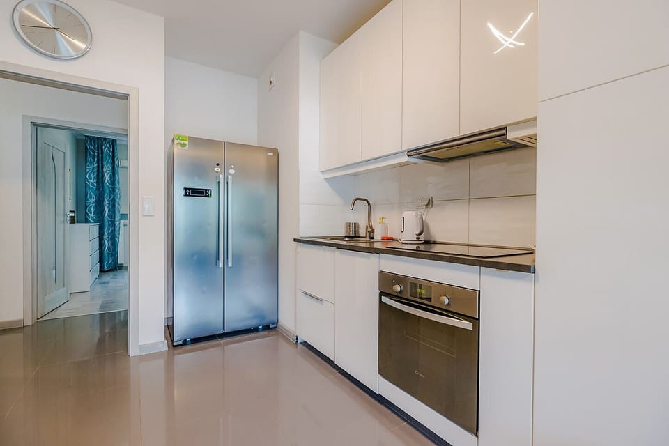 A sleek and modern kitchen equipped with white cabinetry, built-in appliances, and a stylish backsplash.