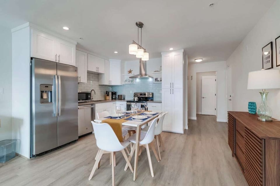 Open-style kitchen with stainless steel appliances + dining for 5 guests. The back foyer is the front entrance to the condo with the guest bedroom + separate bathroom