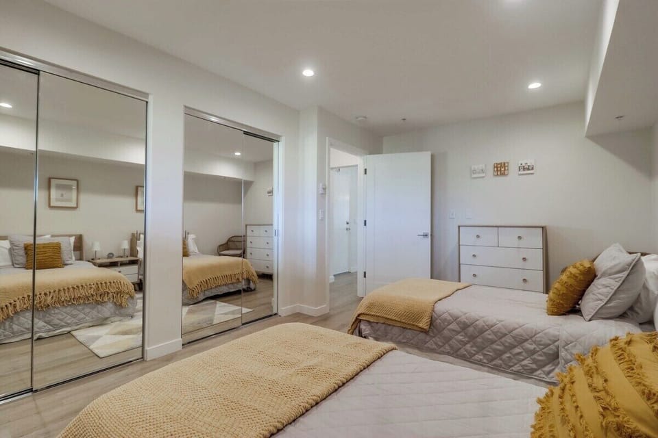 Guest bedroom with 2 twin beds, storage + dresser space. Large closets with iron + board, step stool, cleaning equipment (vacuum, mop, broom) hangers + beach accessories