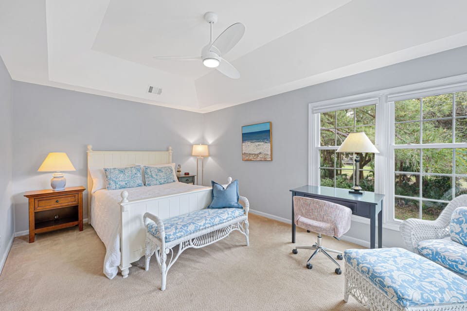 This bright and inviting bedroom offers a relaxing retreat with abundant natural light from oversized windows overlooking peaceful, landscaped views.