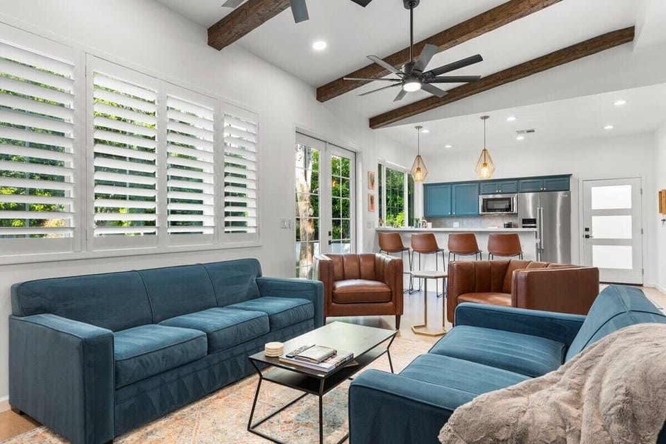 Natural sunlight living room with plantation shutters, exposed wood beams and open kitchen 