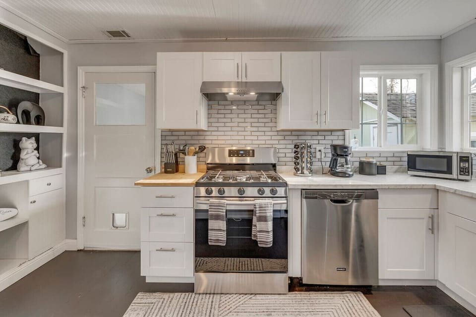 Stocked kitchen with spice rack, knives, cooking utensils, coffee corner, fridge, oven, stove, and microwave