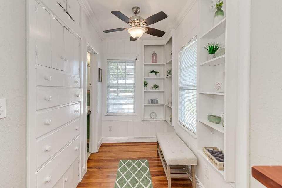 The dressing area is well-lit with natural light and features a ceiling fan with a light. It leads directly to the master bath, creating a bright and convenient space for your daily routine.