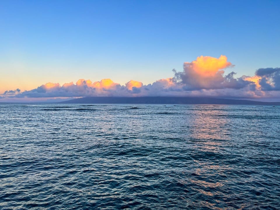 Stunning ocean and sky at dusk, with clouds illuminated in shades of pink and gold over calm waters near the property.