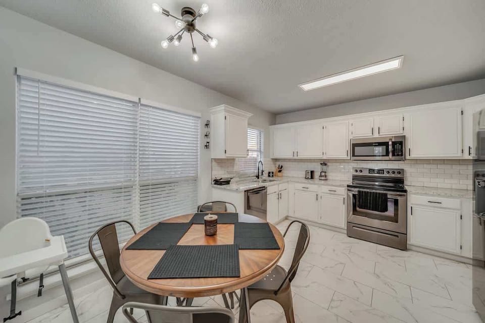 Enjoy meals in this inviting dining space, featuring a modern kitchen, cozy dining table, and a high chair for little ones.
