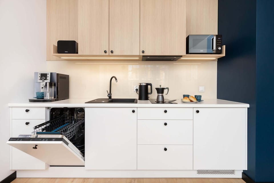 A minimalist kitchen equipped with appliances, a coffee maker, and ample storage.