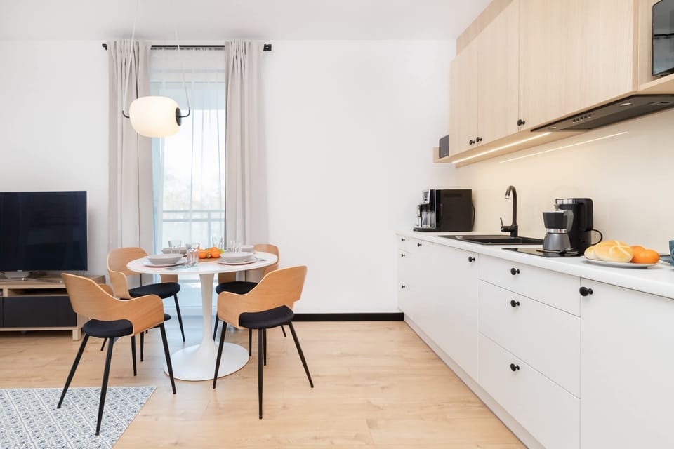 An open-concept space featuring a dining table with chairs, adjacent to a modern kitchen with sleek cabinetry.
