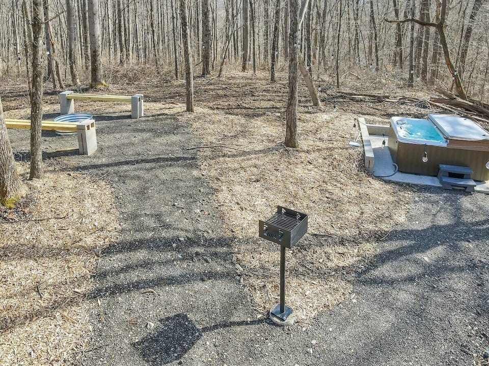 Outdoor space with 7-person hot tub, charcoal grill, fire ring and string lights throughout the area.