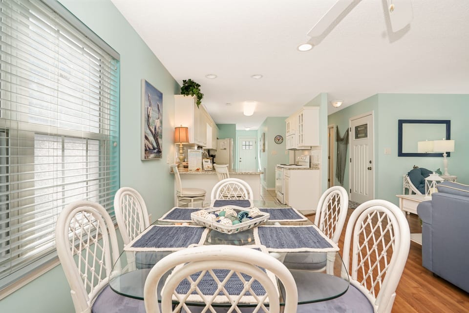 Step into this bright, coastal-inspired dining space where soft mint walls and elegant white furnishings create your perfect gathering spot for memorable meals.