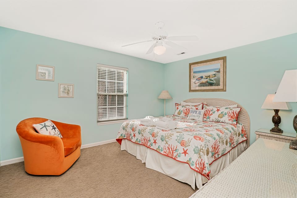 Drift off in your serene coastal bedroom featuring cheerful coral bedding, soft mint walls, and a cozy reading chair perfect for morning coffee.