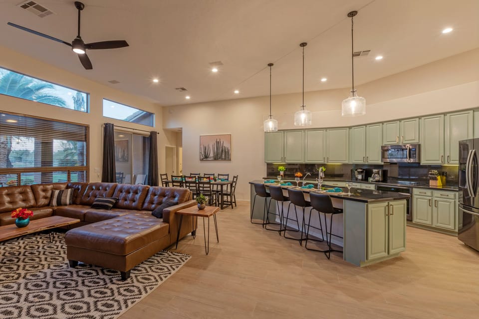 An open and spacious great room features a cozy gathering area, a kitchen with island seating plus a dining area with table seating.
