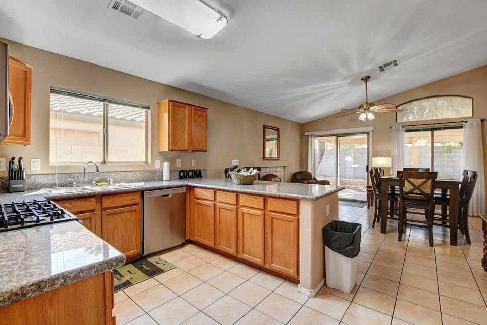 Sunny kitchen with granite, gas range & open dining by backyard patio