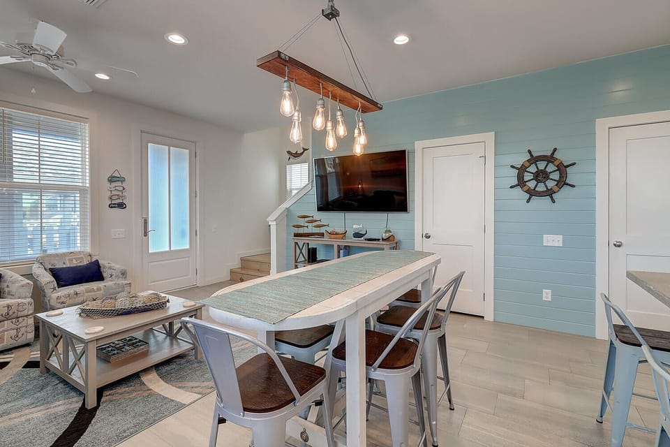 You'll love gathering around this stylish dining table beneath the warm Edison bulb chandelier, with coastal accents creating the perfect atmosphere.