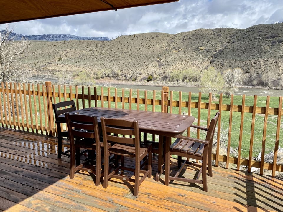 Upper level deck with dining table and chairs for enjoying meals al fresco with the sounds of the Shoshone river