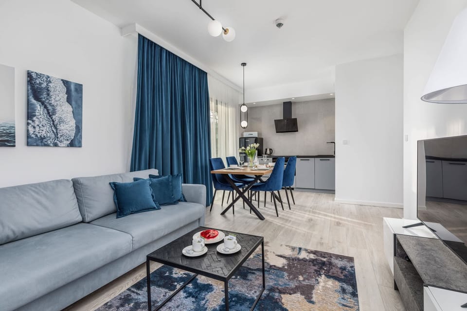 Living and dining area with a blue sofa, a small dining table, and blue curtains, creating a cozy and unified look.