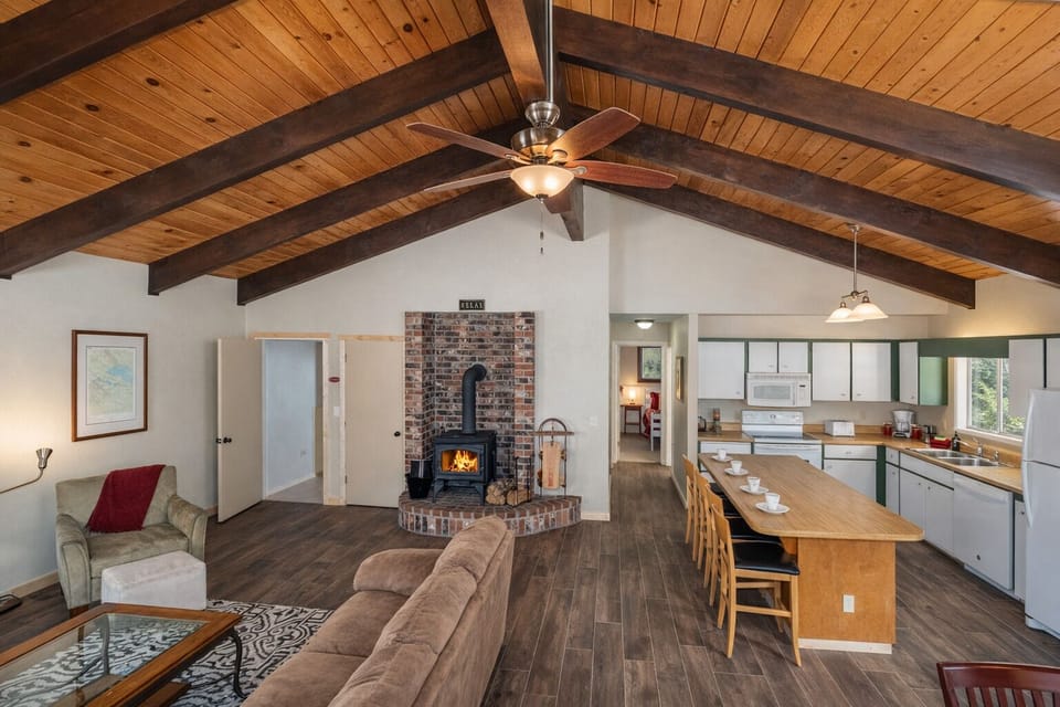 Cozy up in your spacious mountain retreat featuring soaring wood beam ceilings, a crackling fireplace, and open kitchen perfect for group gatherings.