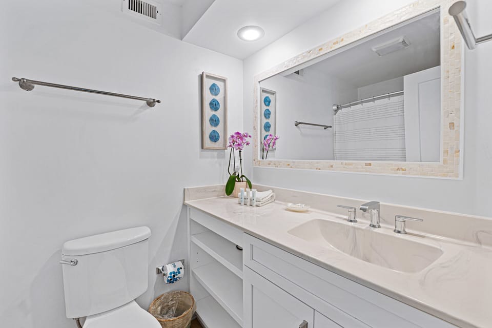 This updated guest bathroom features a spacious vanity with generous storage, a sleek solid-surface countertop, and tub/shower combination.