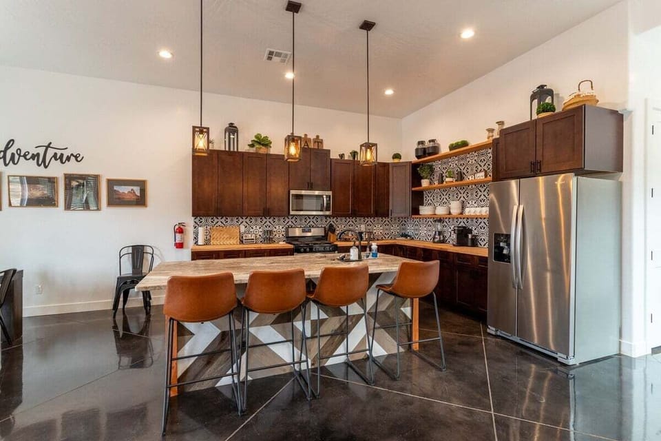 Barstool seating at the kitchen island offers a perfect blend of functionality and style. It highlights rustic elements and is adorned with sleek, modern fixtures.