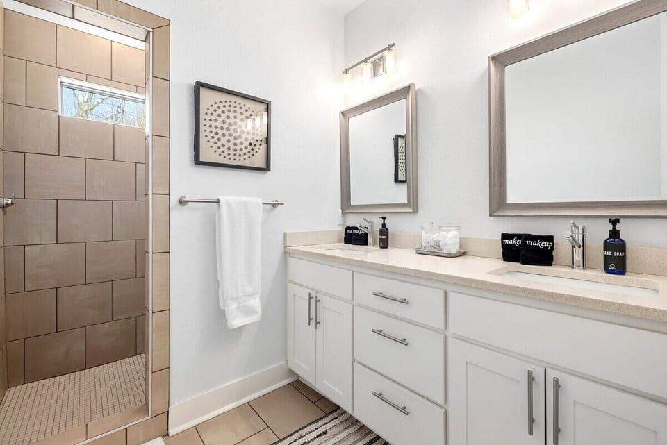 The en suite bath has two double sinks and an open, fully tiled shower.