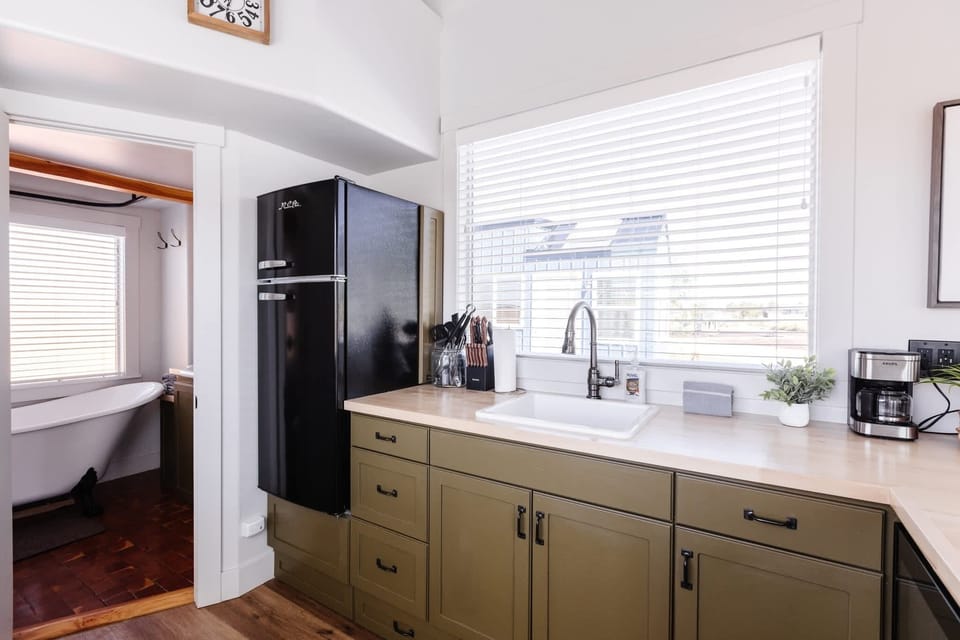 Fully stocked kitchen with farmhouse sink, retro refrigerator, coffee station, and open layout connecting directly to the bathroom and loft area.