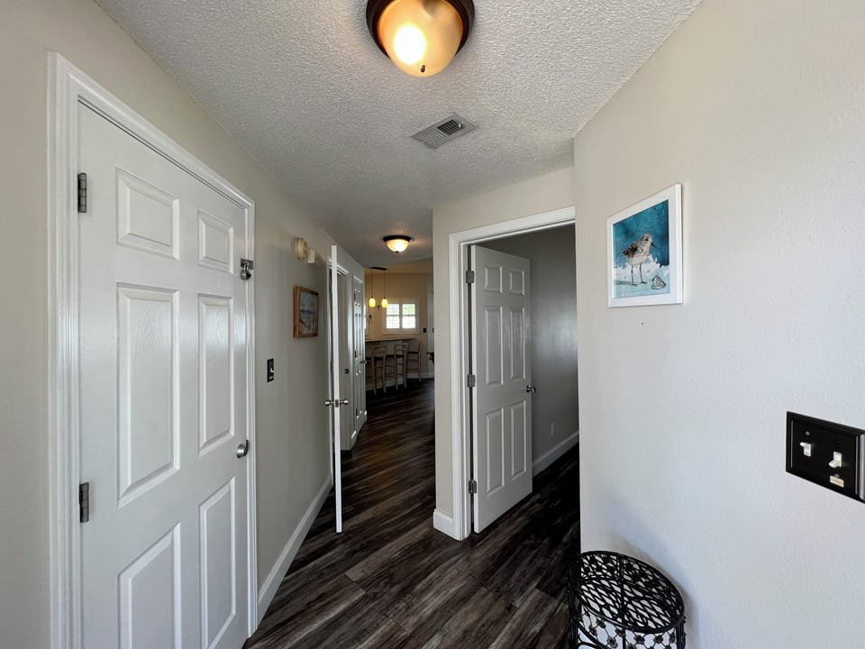 Step into your welcoming hallway with rich wood floors and tasteful coastal artwork guiding you to comfortable living spaces.