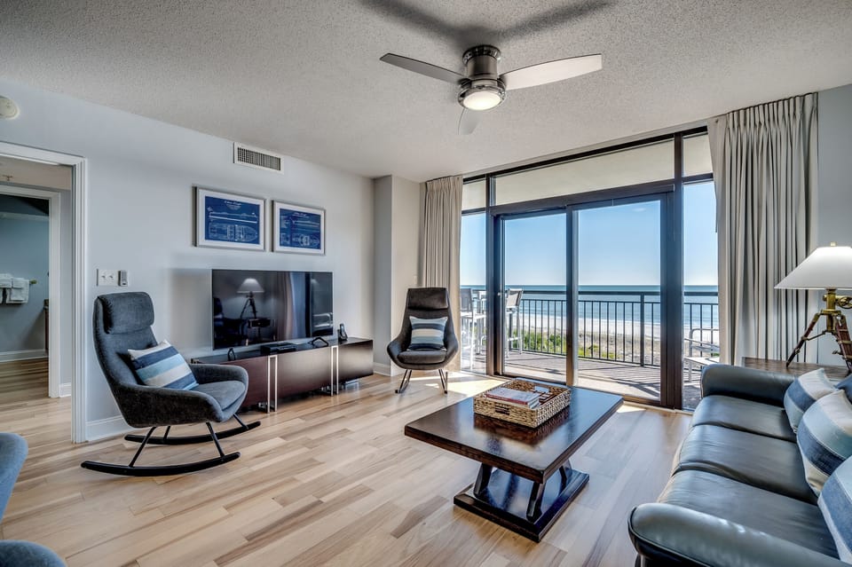 Living room with balcony access and large flat-screen TV