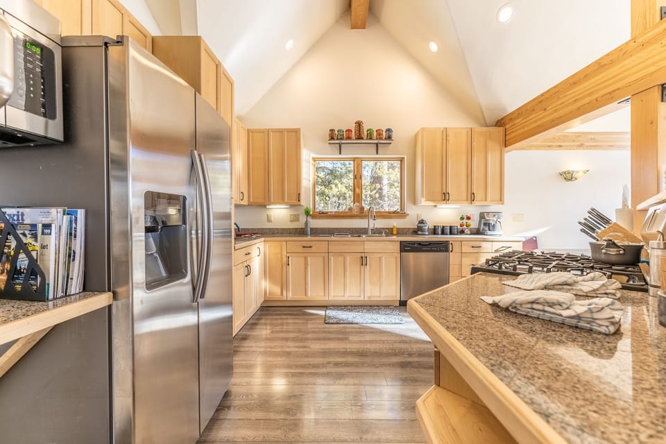 High end full-size kitchen with granite countertops, modern stainless steel appliances and vaulted ceiling.