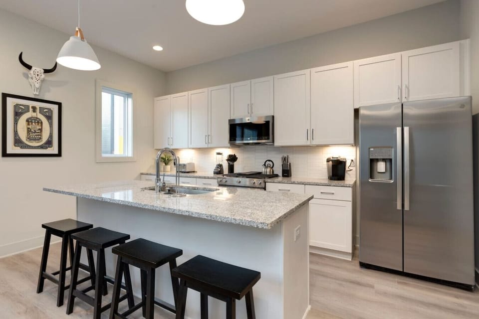 The white modern kitchen with a marble island and premium stainless appliances is a pleasure to cook in.