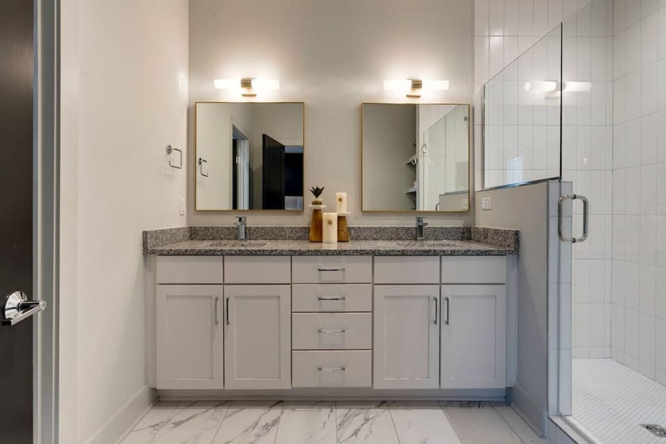 A double vanity bathroom with walk-in shower and well-lit mirrors makes getting ready effortless.