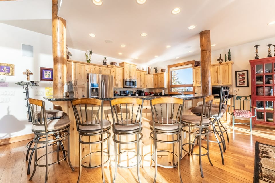 Gather around this inviting kitchen island where warm wood cabinets and rustic beams create the perfect space for your morning coffee and evening conversations.