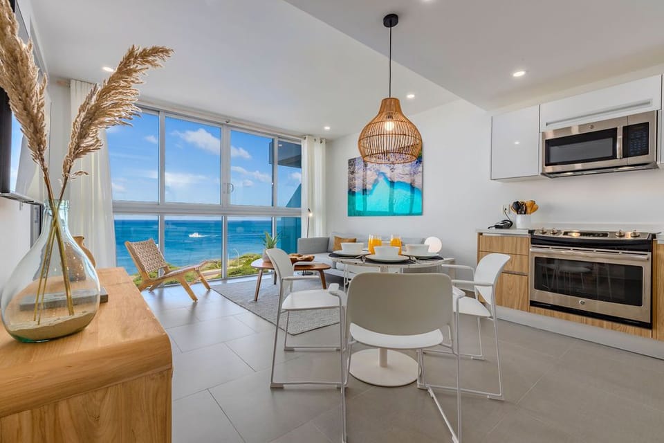 Wake up to endless ocean views through floor-to-ceiling windows that flood your living space with natural light. Sip morning coffee at your dining table as boats drift by on turquoise waters.