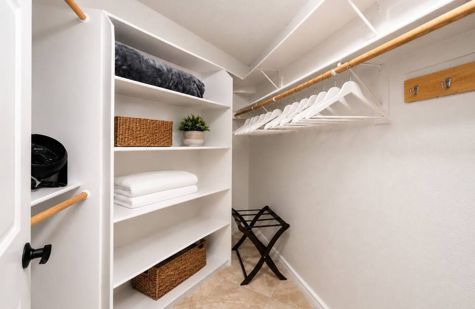 Spacious walk-in closet with hangers, shelves and luggage rack