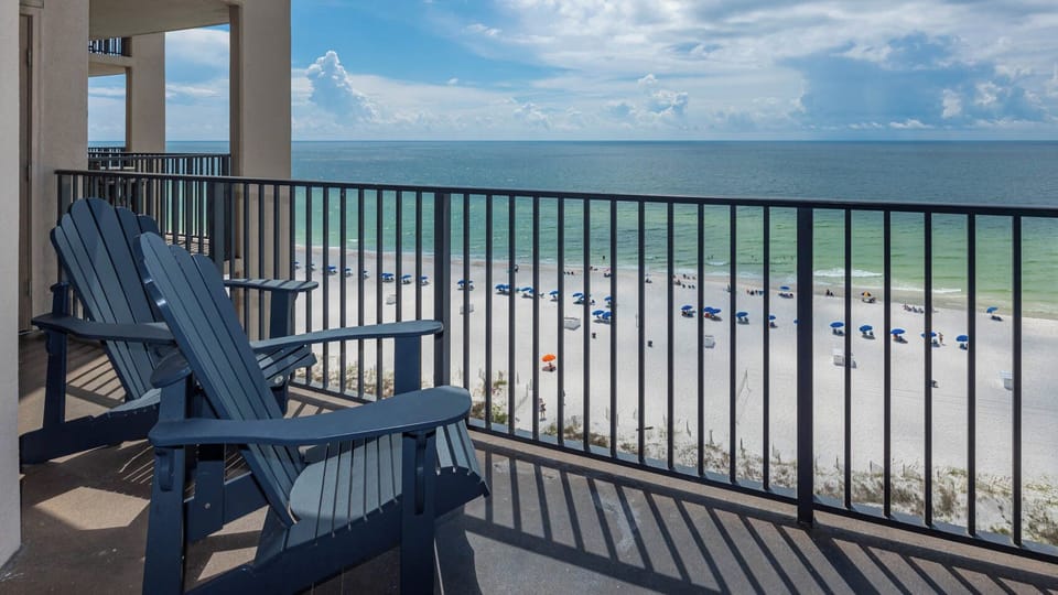 Relax in comfortable chairs while enjoying the expansive view of the beach and water from your balcony