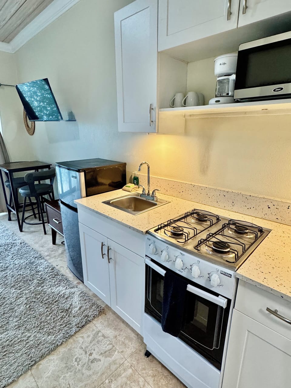 small kitchen with 4 burner stove, toaster, coffee maker and microwave